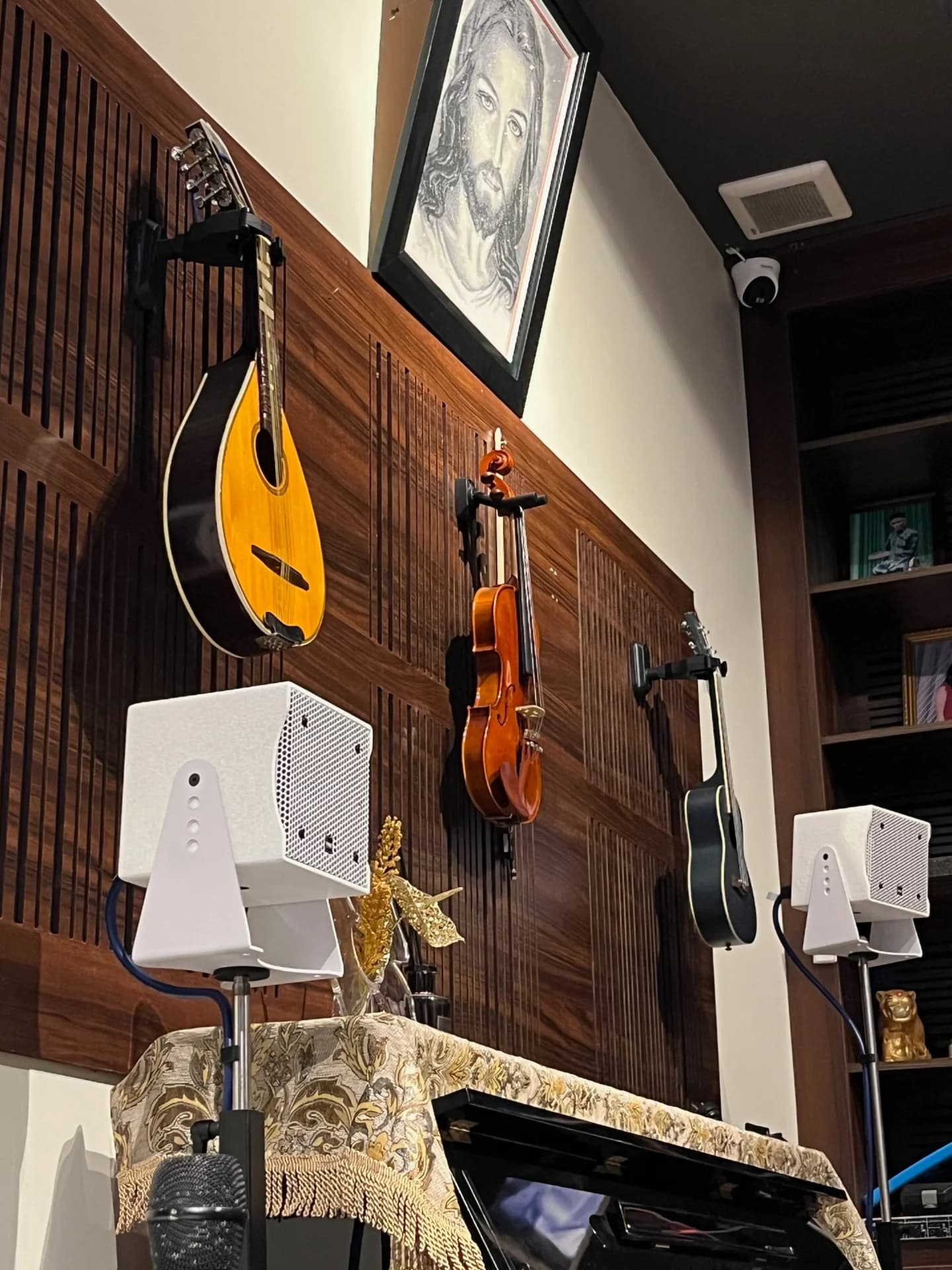 Một cặp loa YME CS lắp đặt sát tường ngay dưới góc trưng bày đàn mandolin, violin và guitar trên vách gỗ tại nhà riêng.