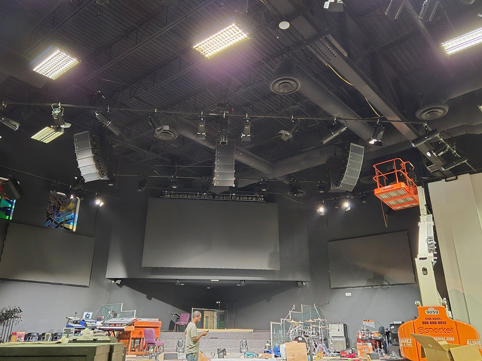 YME Audiotechnik Line Array và đèn sân khấu treo trên khung trần đen, đội kỹ thuật đang thi công lắp đặt hệ thống âm thanh ánh sáng cho sân khấu.