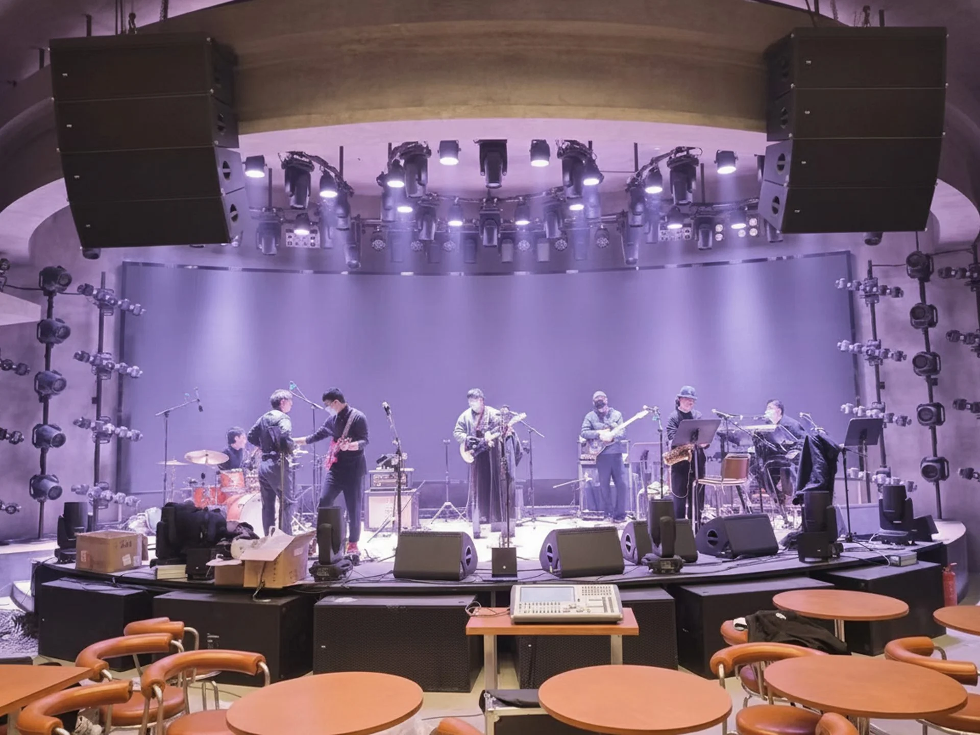 Ban nhạc soundcheck trên sân khấu nhà hát với dàn loa Line Array treo hai bên và bàn mixer kỹ thuật số phía trước.