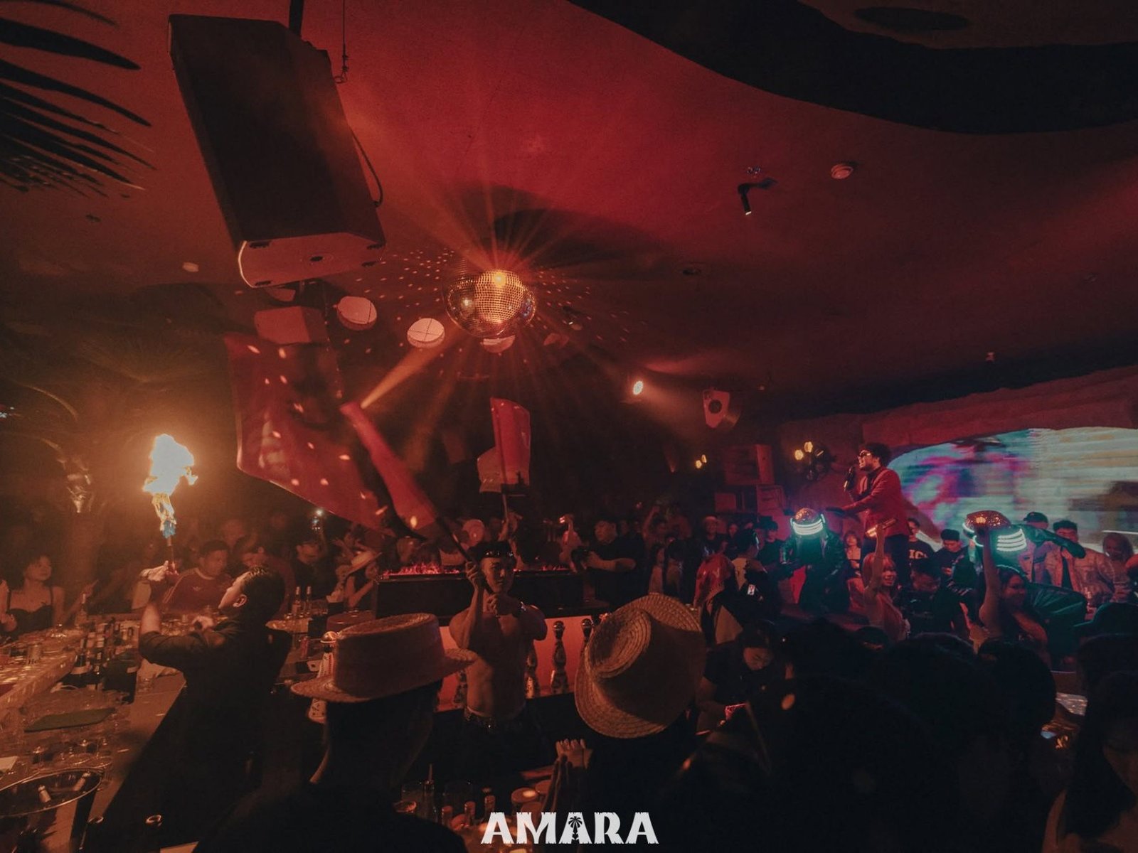 Không gian Amara Club về đêm với sân khấu, quả cầu disco và khách tham dự đông kín sàn.